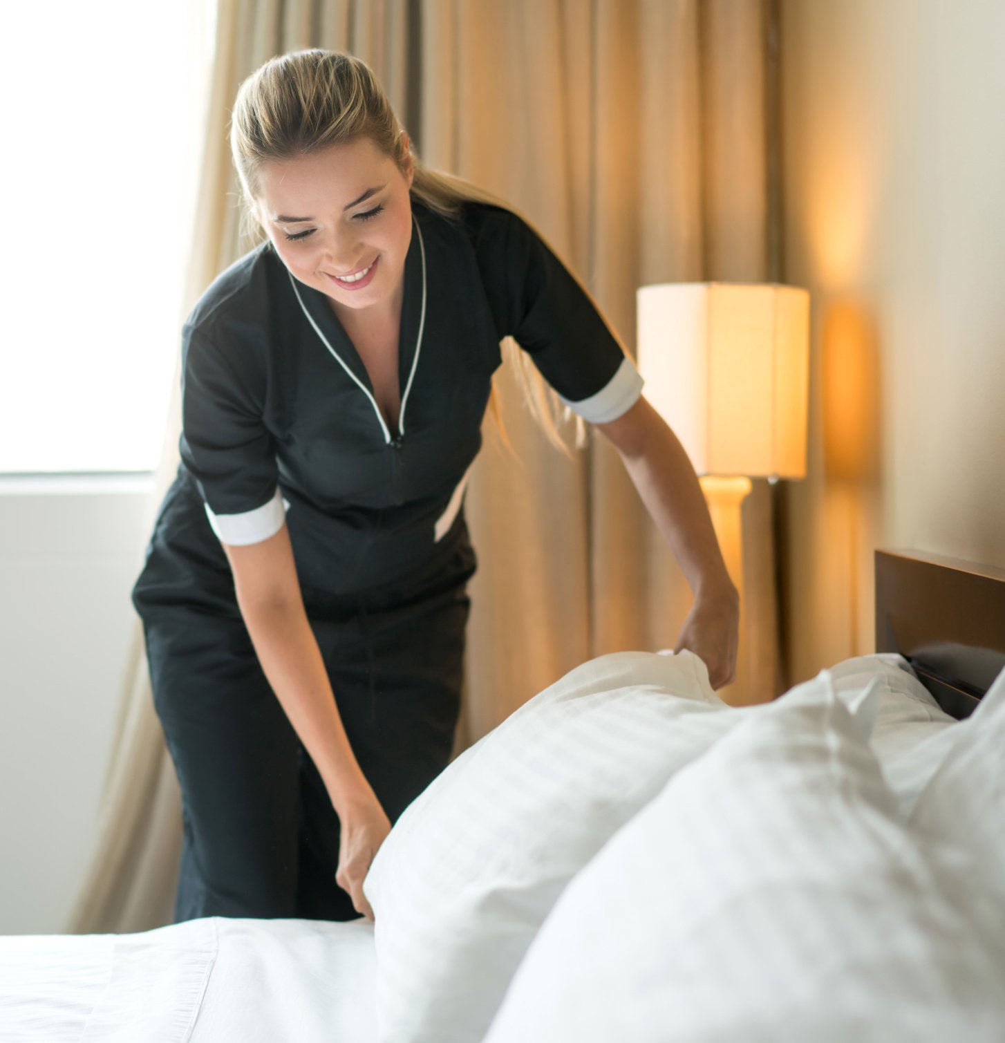 Housekeeper making the bed at a hotel